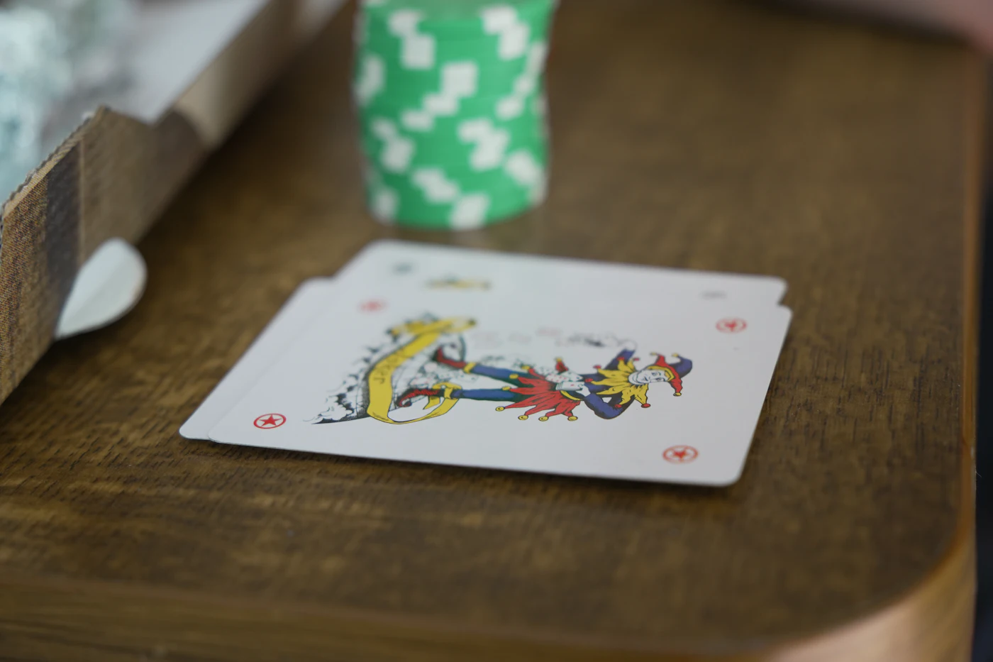 Kartu joker dan tumpukan kartu remi di atas meja kayu